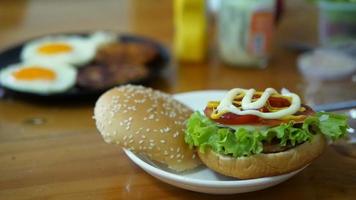 Señora haciendo desayuno de hamburguesa con huevos borrosos sobre fondo de mesa de madera video