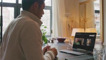 Joven asiático con videollamada con dos mujeres en la pantalla del portátil video