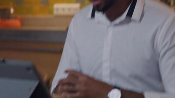 Hands of mature black man, in front of laptop. One hand moves, gesture. Tilt up, man talks vividly, smiles, gestures. video