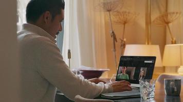 Asian young man having video-call with two women on laptop screen video