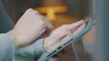 Close-up of hands of Asian young man, holding tablet, tapping, scrolling video