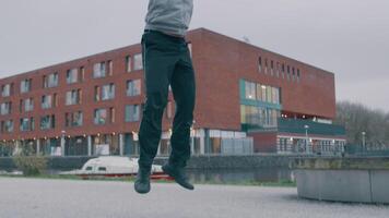 Young Asian man, in park, doing physical exercise, by doing push up, standing up whilst jumping and jumping with hands in the air, four times. Slow motion. video