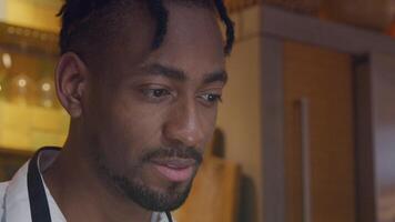 Close-up of mature black man, looks into light of device device not shown, turns head and back, watches device again, laughing, talking vividly, nodding video