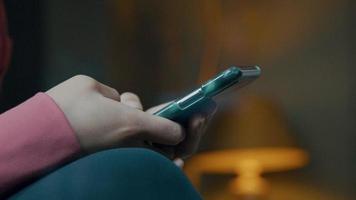 close-up das mãos de uma jovem negra digitando na tela do celular com os polegares