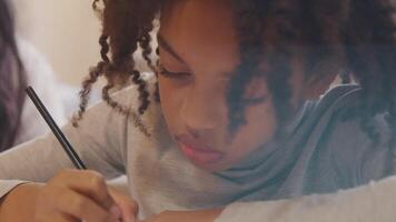 Girl sits next to woman, writing with pencil in work book, talks, looks up, talks and writes again video