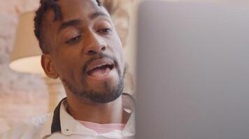 Mature black man, laptop in front talks vividly, gesturing, whilst having call.Head-shoulders shot. Blurred laptop cover on the right. video