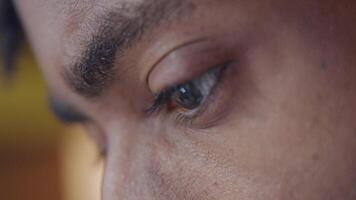 Close up of forehead, eyebrows and dark brown eyes of mature black man. Eyes searching, light of screen device reflecting. Profile video