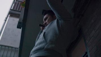 asiatisk ung man gör pull ups utanför, med handtag på bar, ryggen nära väggen video