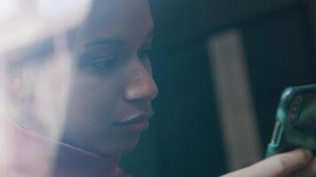 Close-up of black young woman, holding mobile phone in front of her face, whilst typing on it video