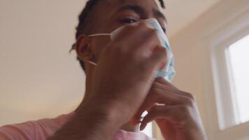Mature black man looks into lens camera, whilst putting on face mask. Man adjusts mask and leaves. Camera moves towards head man video