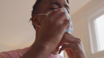 Man puts on face mask, adjusts mask and leaves video