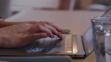 primo piano delle mani della donna asiatica che digita sulla tastiera del computer portatile video