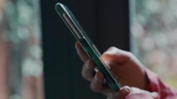 close-up van handen van zwarte jonge vrouw, scrollen en typen, beweegt telefoon dichter bij haar gezicht video