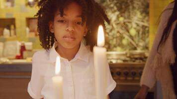 menina observa duas velas acesas na frente dela, apaga uma. a outra vela precisa tentar três vezes, garota ri, dá um passo para trás video