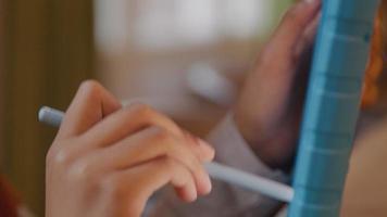 Close up of hand girl, holding stylus pen, moving it up and down on screen of tablet, held upright