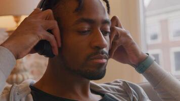 Mature man sits and puts headphone on his ears, moving his head slowly on rhythm, smiles video
