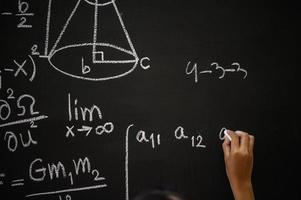 Student writes the formula with white chalk on the blackboard photo