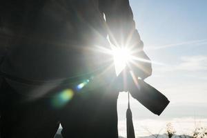 Silhouette of young photographer holding a camera with mountain landscape photo