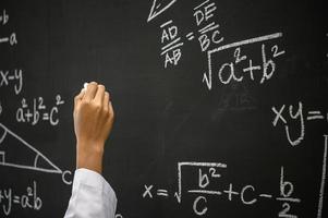 Student writes the formula with white chalk on the blackboard photo