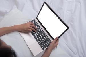 Woman using laptop while sitting on bed photo