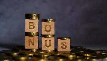 palabra de bonificación en letras de cubo de madera colocadas en una moneda de oro foto