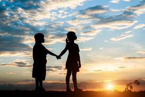 silueta de niños jugando al atardecer foto