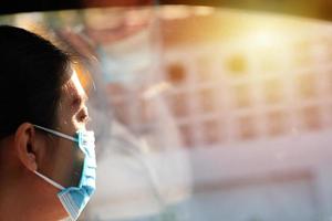 Woman wearing a mask feeling alone and sad sitting in a car during Coronavirus Disease photo