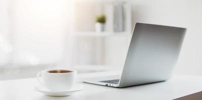 taza de café en la mesa de trabajo con laptop foto