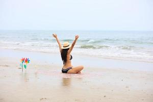 Mujer levantando las manos en una playa expresando felicidad y relajación foto