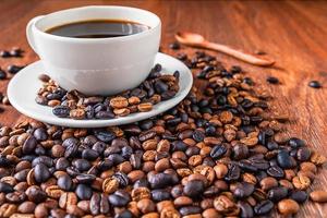 Taza de café y granos de café en una mesa de madera foto