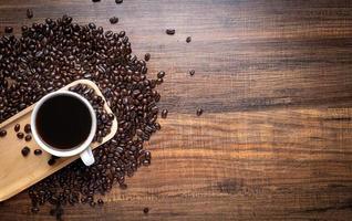 Granos de café con taza sobre mesa de madera