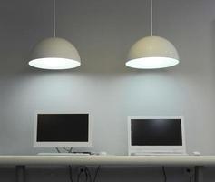 Espacio de trabajo tipo loft, computadoras en una mesa con lámparas. foto