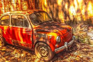Viejo coche oxidado delante de una pared sucia foto