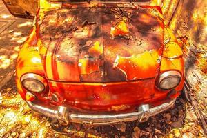 Viejo coche oxidado delante de una pared sucia foto