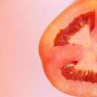 tomate fresco en rodajas sobre un fondo rosa foto