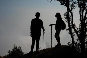 Silhouette of a couple hikers on the top of a mountain photo