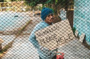 mendigos en una valla con mensajes para personas sin hogar por favor ayuden foto