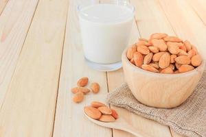 Almond milk in glass with almonds on the table photo