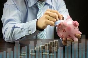 Businessman putting money coins in piggy bank photo
