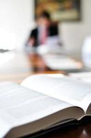 Open book on an office desk with a blurred man in the background photo