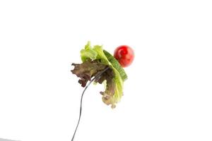 Fresh mixed vegetables on a fork isolated on white background photo