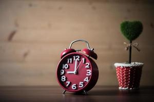 Tree of heart with red alarm clock on wooden table photo