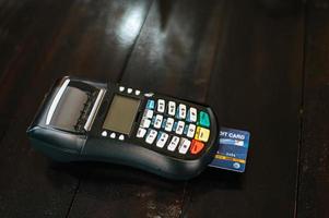 Credit card machine with inserted credit card on wood table photo