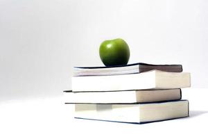 Pile of books with green apple white background photo