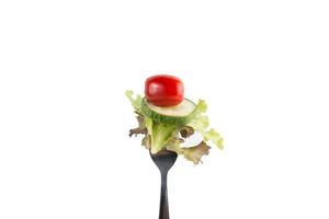 Fresh mixed vegetables on a fork isolated on white background photo