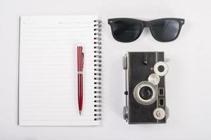 Sunglasses and vintage camera with notepad isolated on a white background photo