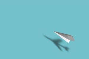 Avión de papel con la sombra de un avión real sobre fondo azul.
