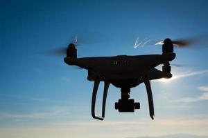 White drone hovering in a bright blue sky photo