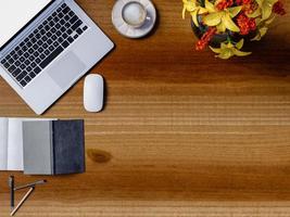 Top view of a wooden table in office with laptop and coffee cup photo