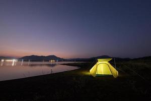 Camping tent near water at dusk